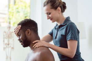 Woman physical therapist adjusting man's neck